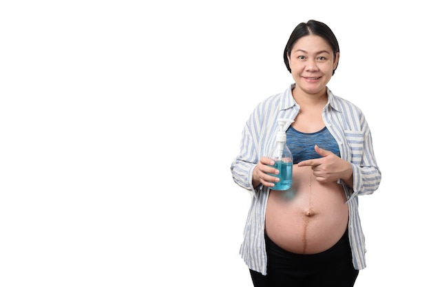 Smiling Asian pregnant woman holding a blue sanitizer hand gel and pointing finger to the gel