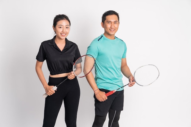 Smiling asian woman and man standing holding racket on isolated background