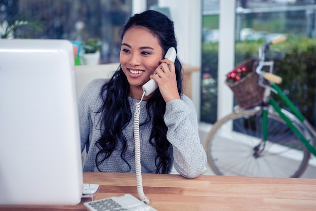 Smiling Asian woman on phone call in office