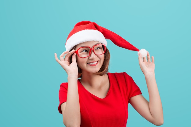 Smiling asian woman portrait with christmas santa hat isolated on blue background.