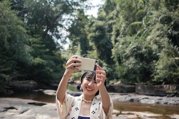 Smiling asian woman self portrait photography at the waterfall