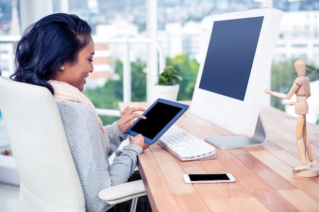 Smiling Asian woman using tablet sitting in office