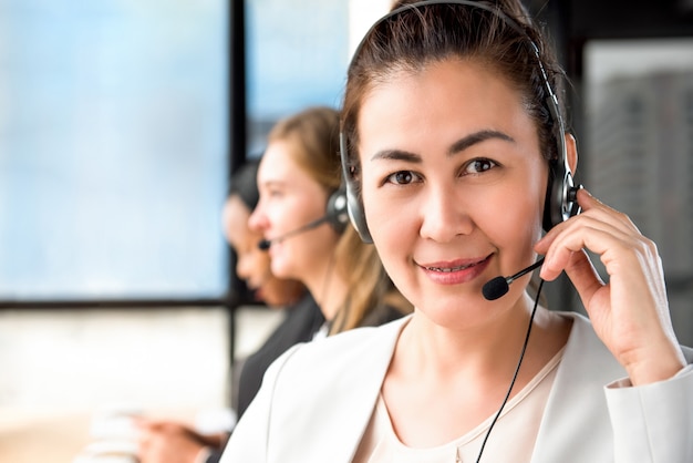 Smiling Asian woman working in call center with international team 