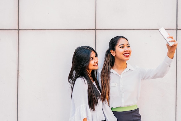 Smiling Asian women taking selfie on smartphone