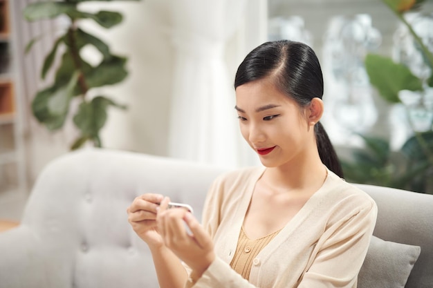 Smiling attractive asian woman looking at her perfect nails after filing them