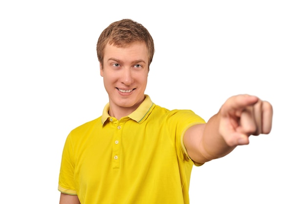 Smiling attractive handsome guy in casual yellow Tshirt pointing forward isolated white background