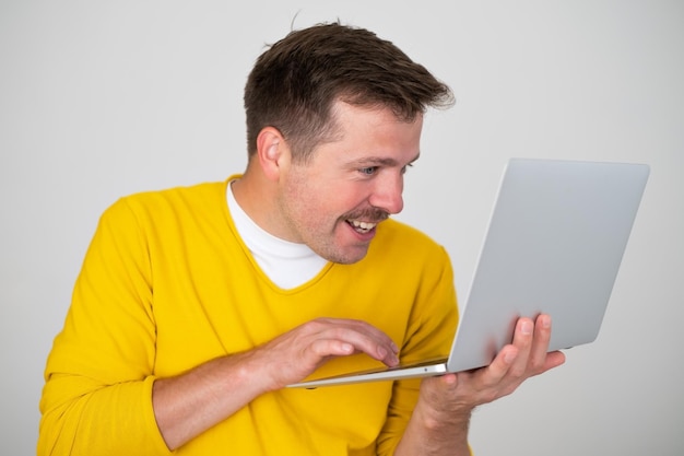 Smiling attractive man holding laptop pc computer surfing in internet