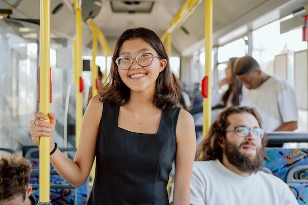 Smiling attractive student in strange city moving by public transport girl holding  the railing