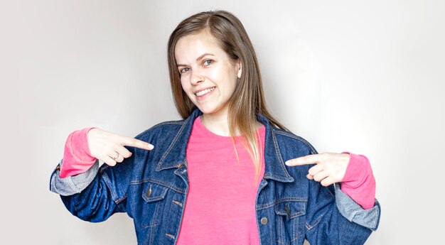 Smiling attractive young woman pointing away over white background