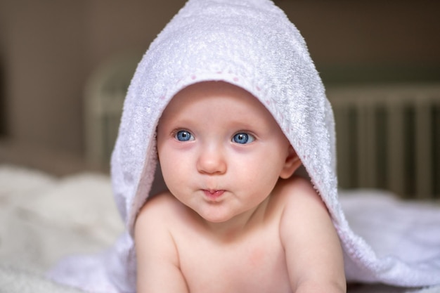 Smiling baby looking at camera under a white blanket towel