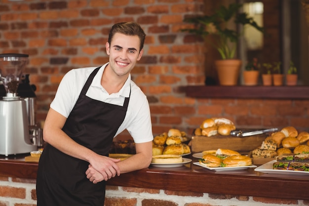 Smiling barista leaning against counter