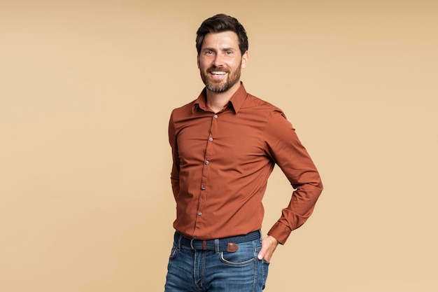 Smiling bearded businessman manager looking at camera while posing isolated on beige background