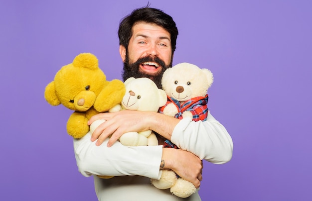 Smiling bearded man hugs Teddy bears. Happy Bearded man with plush toys. Gift and present.