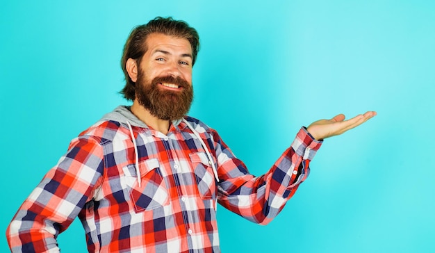 Smiling bearded man shows something on palm hand with copy space for product advertising discount