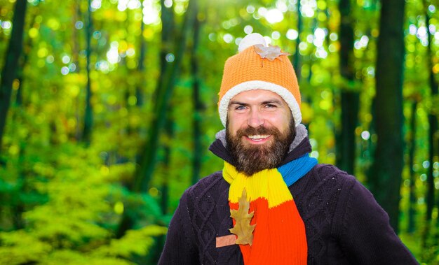 Smiling bearded man in warm clothes in park in sunny day fall season male autumn fashion