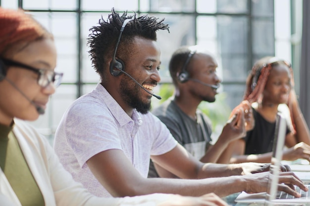 Smiling beautiful African American woman working in call center with diverse team