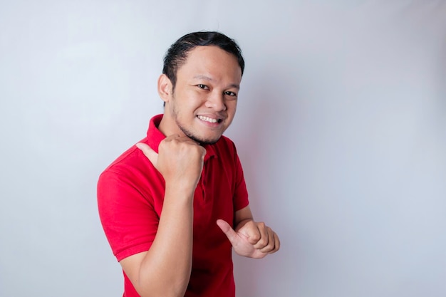 Smiling beautiful Asian man pointing finger to empty space beside him isolated white background