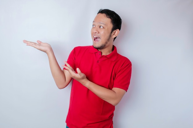 Smiling beautiful Asian man pointing finger to empty space beside him isolated white background