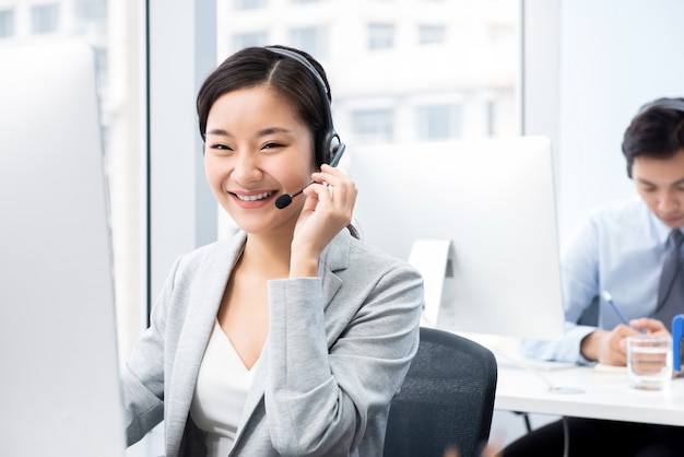 Smiling beautiful Asian woman working in call center office as a customer service operator