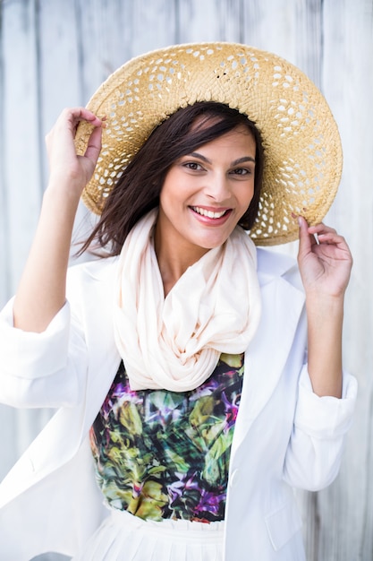 Smiling beautiful brunette wearing straw hat and looking at camera