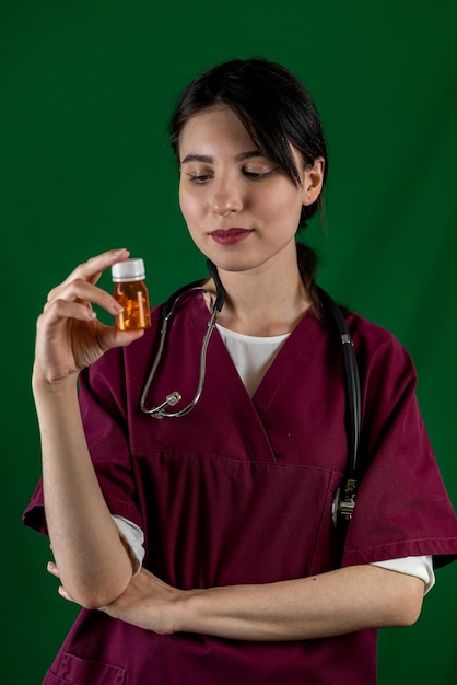 Smiling beautiful female doctor with stethoscope in medical gown holding bottle with pills isolated on background A female doctor Medical staff concept of medicine