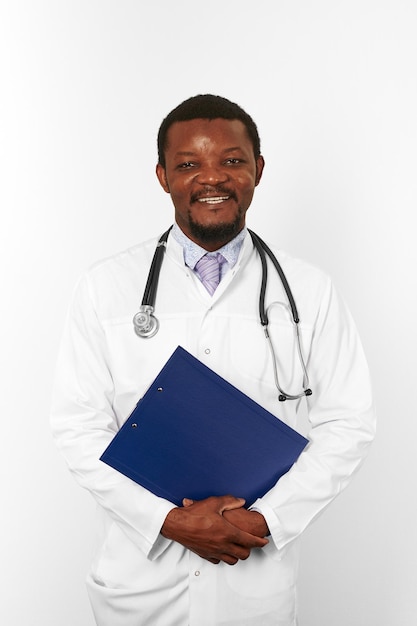 Smiling black bearded doctor man in white robe holds medical clipboard isolated on white background