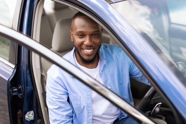 Smiling black man driving new car in the city