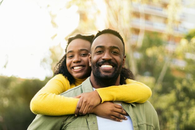 smiling black man giving piggyback ride to his girlfriendfront view