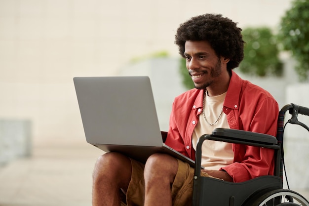 Smiling Black man with disability working on laptop