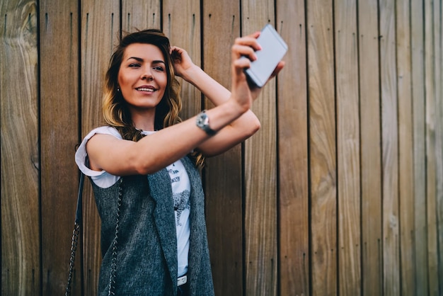 smiling blogger posing for camera making selfie on modern telephone for updating profile picture