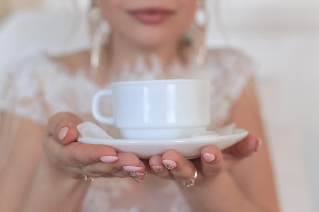 smiling blonde bride in a hotel room drinking coffee