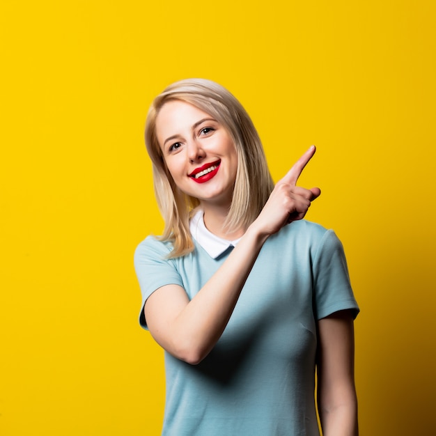 Smiling blonde girl in blue dress on yellow space