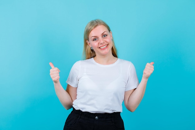 Smiling blonde girl is showing perfect gestures on blue background