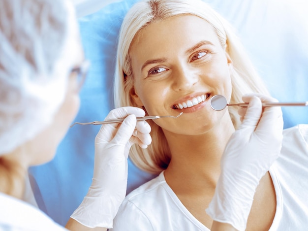 Smiling blonde woman examined by dentist at dental clinic Healthy teeth in medicine concept