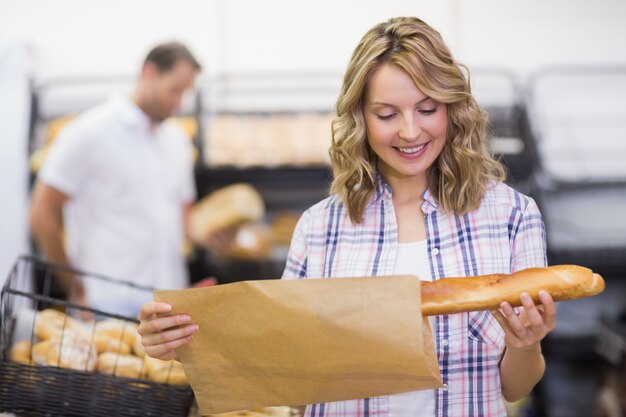 Smiling blonde woman looking at a bread 