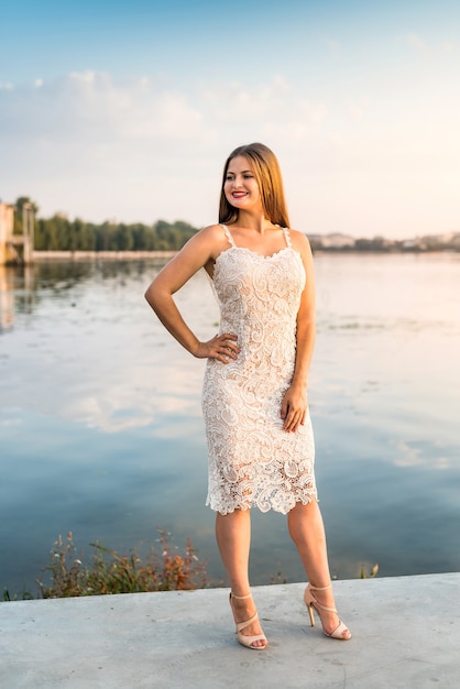 Smiling blonde woman posing in fashion dress on beach