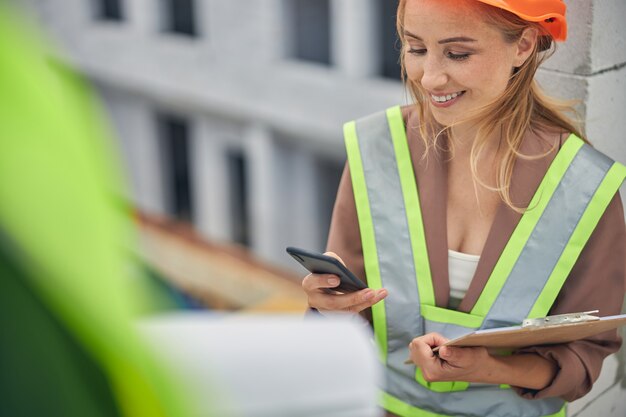 smiling blonde woman reading a text message on her cellular phone