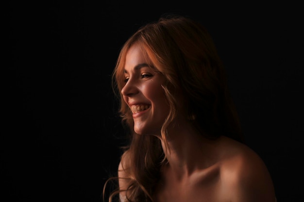 Smiling blonde woman in the shadows Studio shot