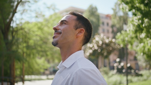 Smiling boss enjoying sunlight at summer city closeup brunette man at park