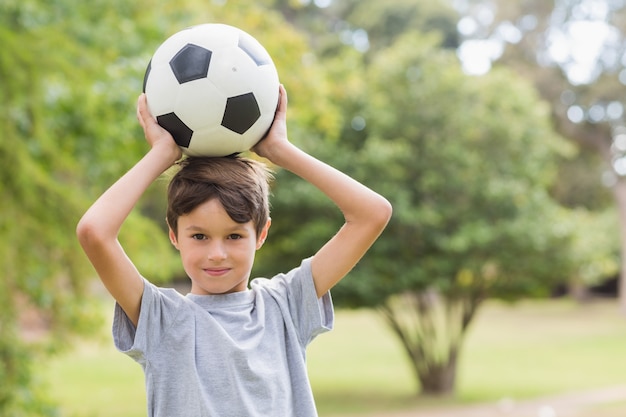 Photo smiling boy holding a soccer ball in the park