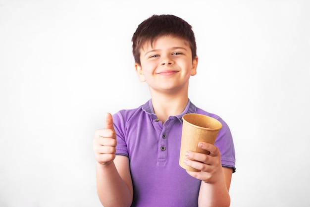 Smiling boy holds a plastic and a paper drinking cup in the hands. Promotion of non-use of plastic. Zero waste concept