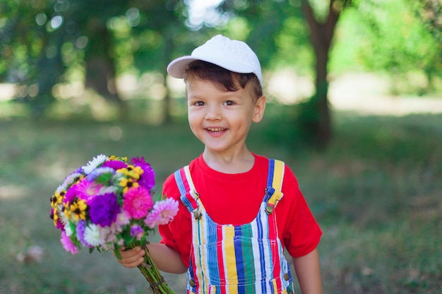 Smiling boy with a bouquet of wildflowers a surprise for mom in the holiday a child with flowers in ...