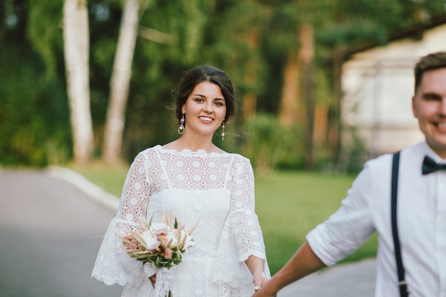 smiling bride brunette young woman with the boho style bouquet with groom