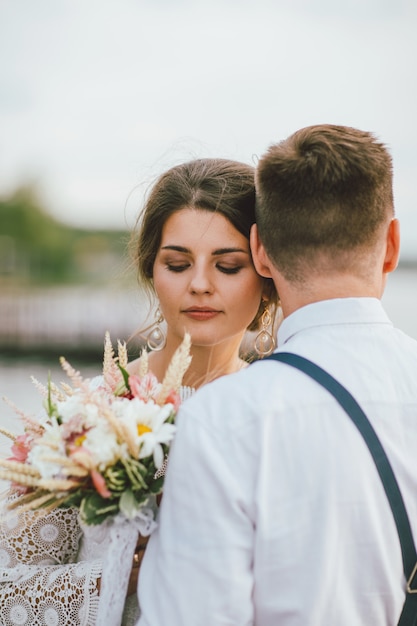 smiling bride brunette young woman with the boho style bouquet with groom