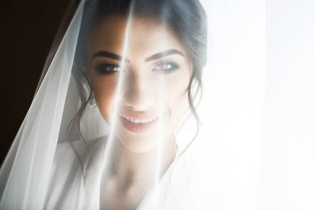 Photo smiling bride looks from under the veil