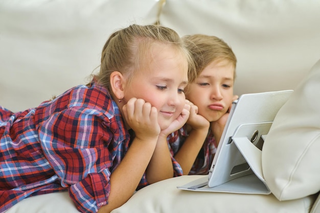 Smiling brother and sister with tablet on the sofa in living room