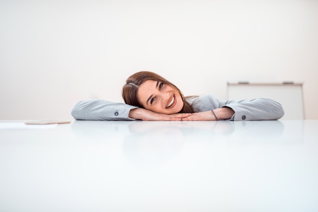 Smiling brunette businesswoman lying on a table and looking at camera, copy space.