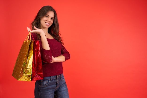 Smiling brunette girl with Christmas shopping bags on an orange background