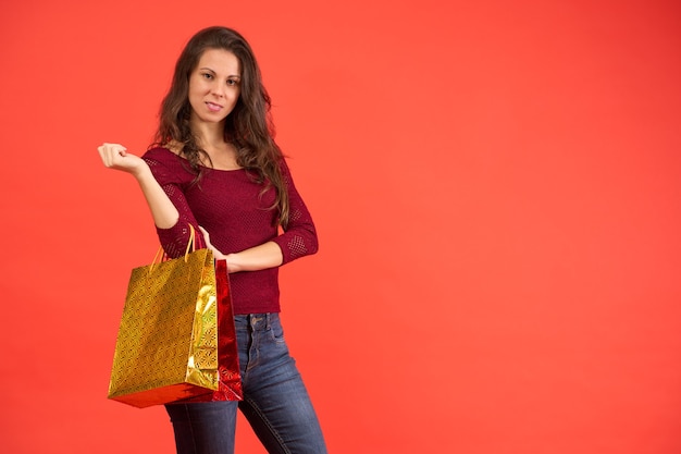 Smiling brunette girl with Christmas shopping bags on an orange background