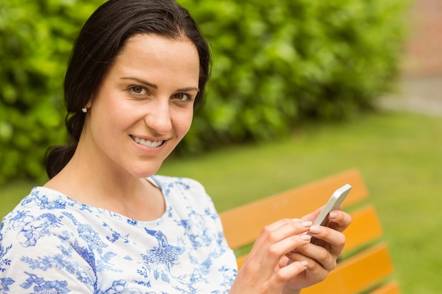 Smiling brunette using her smartphone